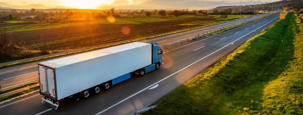 Large Transportation Truck on a highway road through the countryside in a beautiful sunset